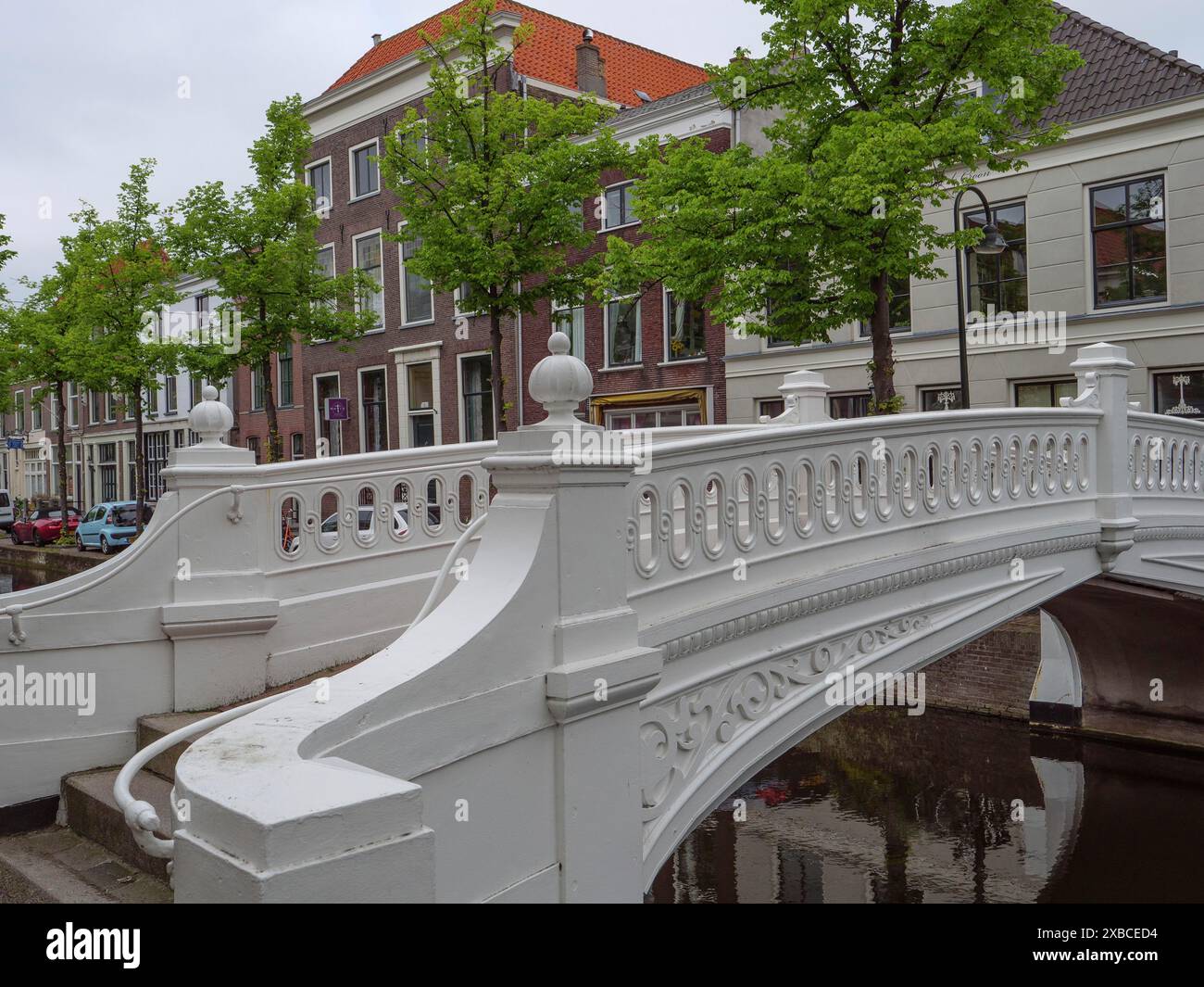 Ponte decorativo bianco su un canale, circondato da case e alberi verdi, Delft, Olanda, Paesi Bassi Foto Stock