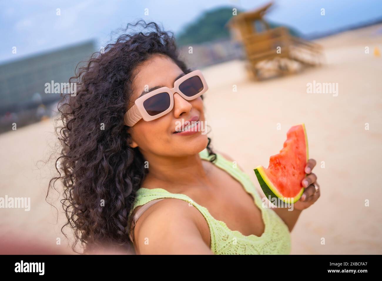 Selfie di donna latina in estate in spiaggia in vacanza con cappello e anguria Foto Stock