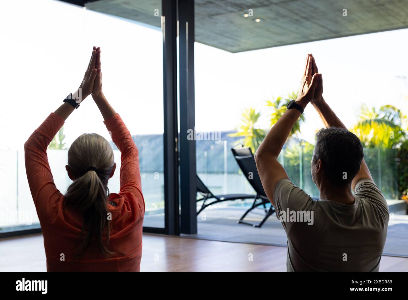 Una coppia matura birazziale e matura sta praticando yoga insieme a casa, a casa Foto Stock