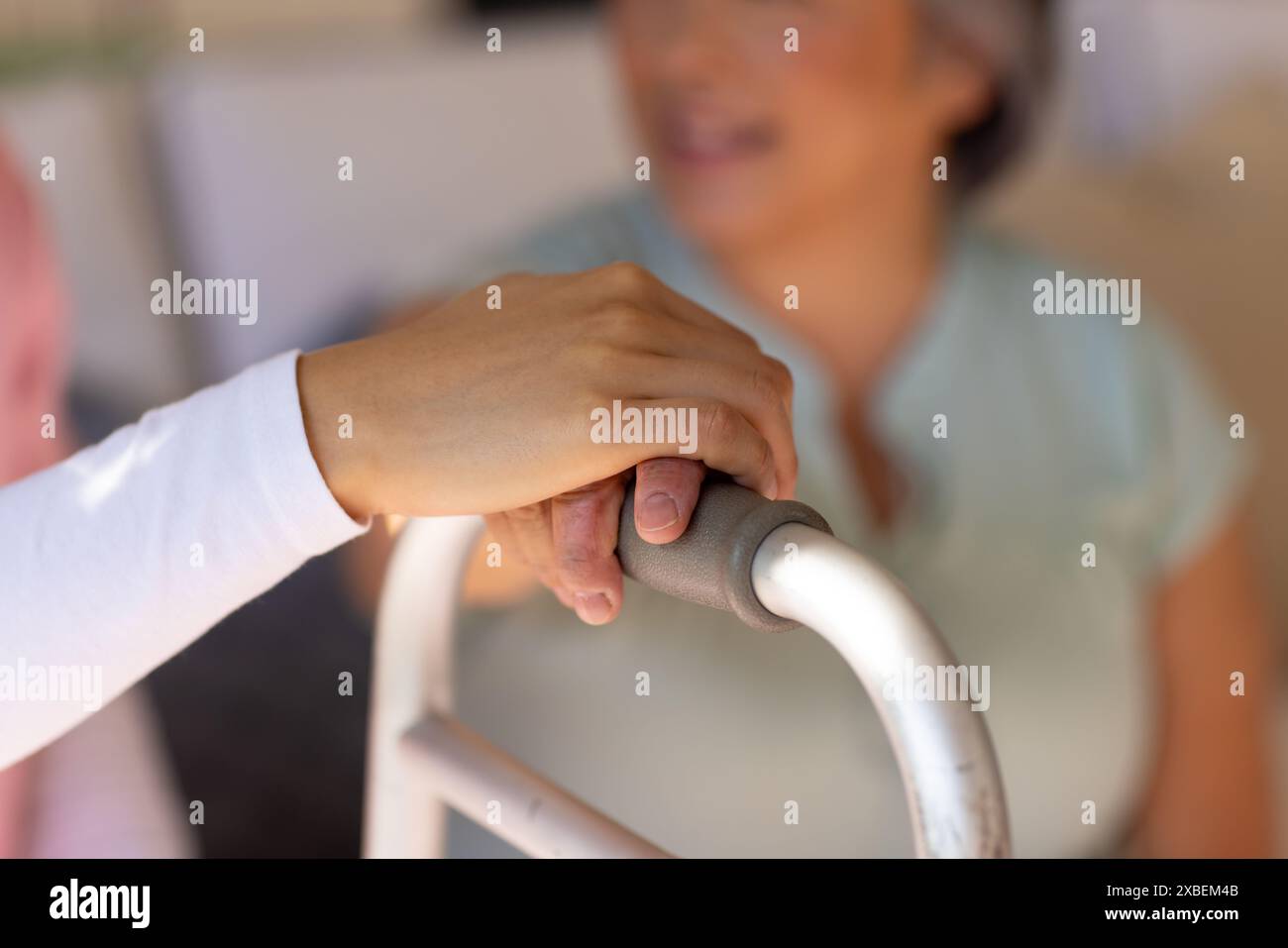 Infermiera asiatica operatore sanitario che tiene la mano di anziana donna asiatica su camminatore, a casa Foto Stock