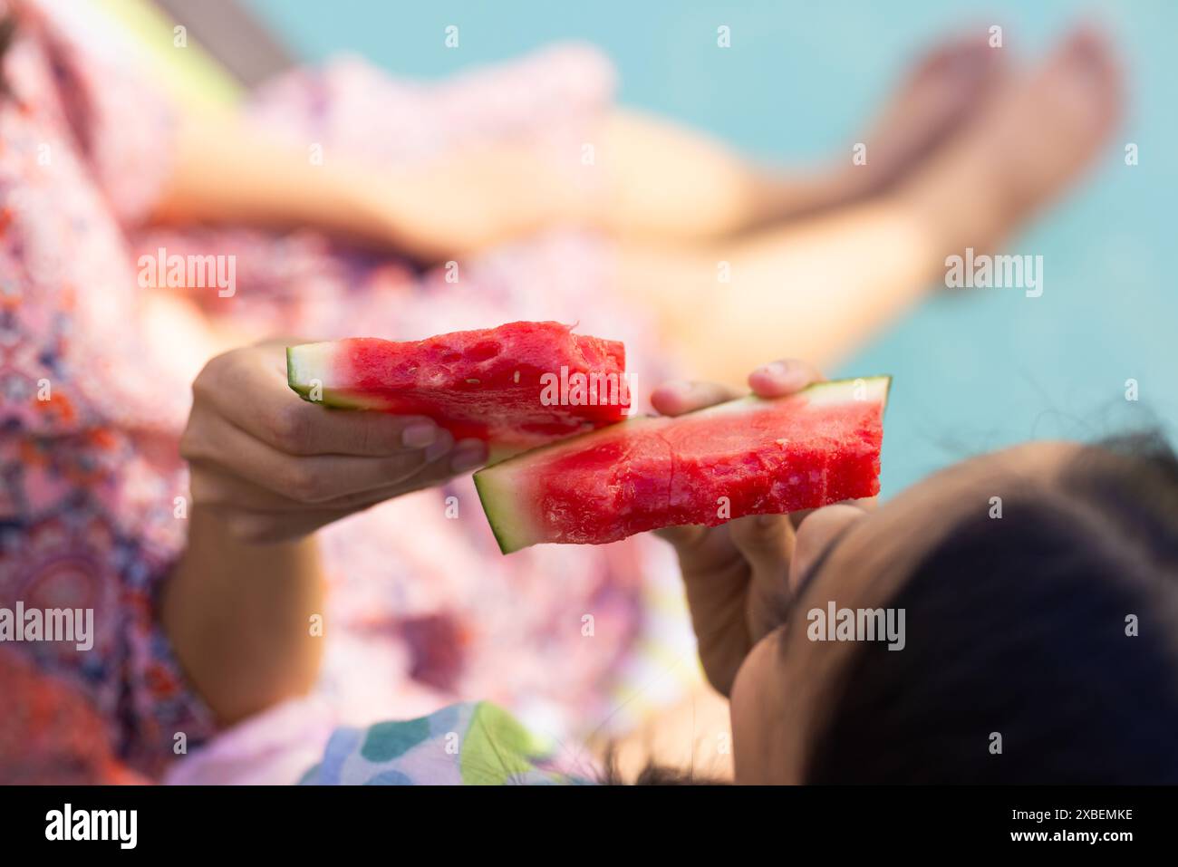 Due giovani sorelle birazziali si godono le fette di anguria insieme, a casa Foto Stock