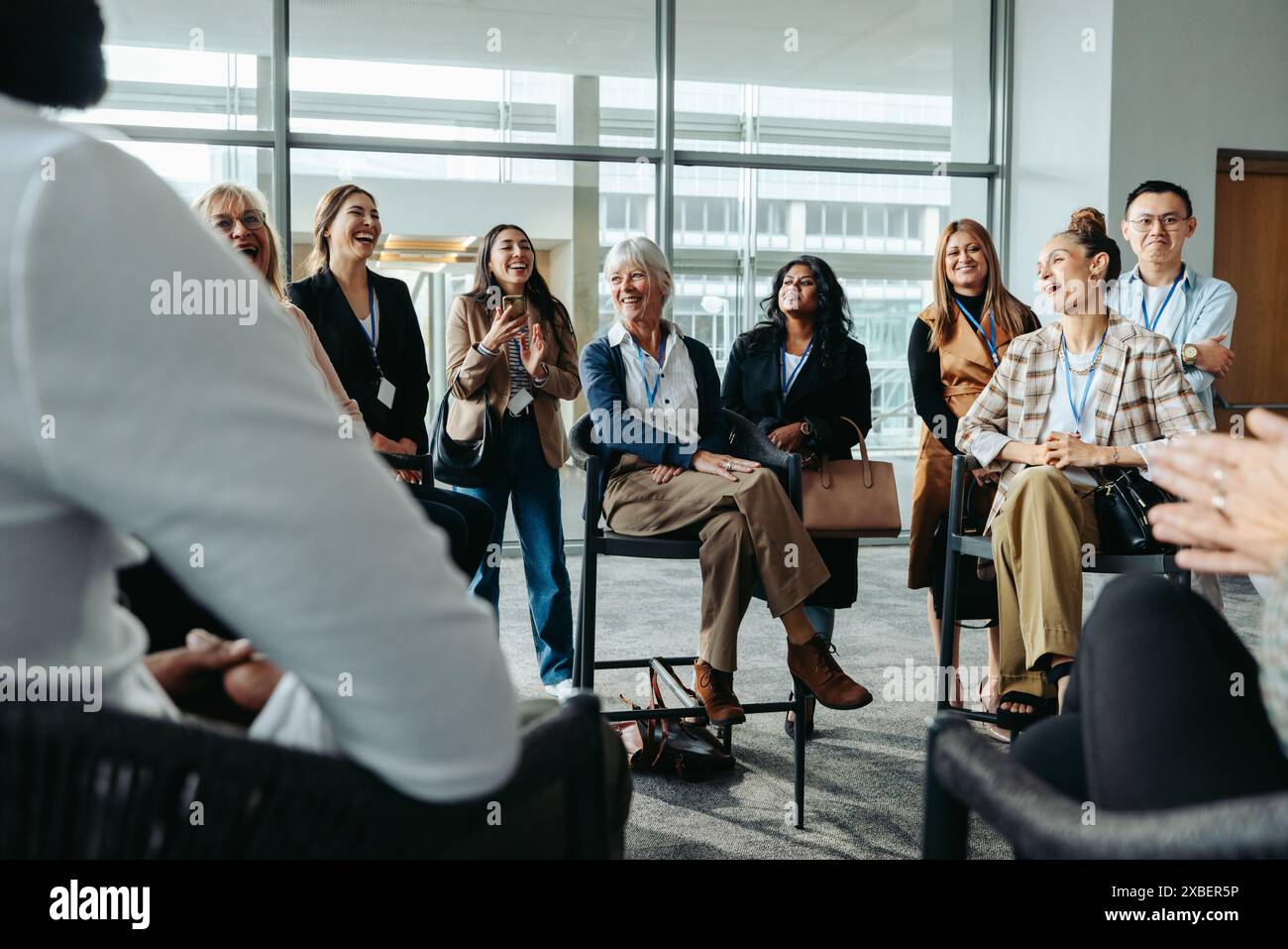 Un gruppo diversificato e felice di colleghi che ridono e coinvolgono durante una riunione d'ufficio, rappresentando il lavoro di squadra e la cultura aziendale. Foto Stock