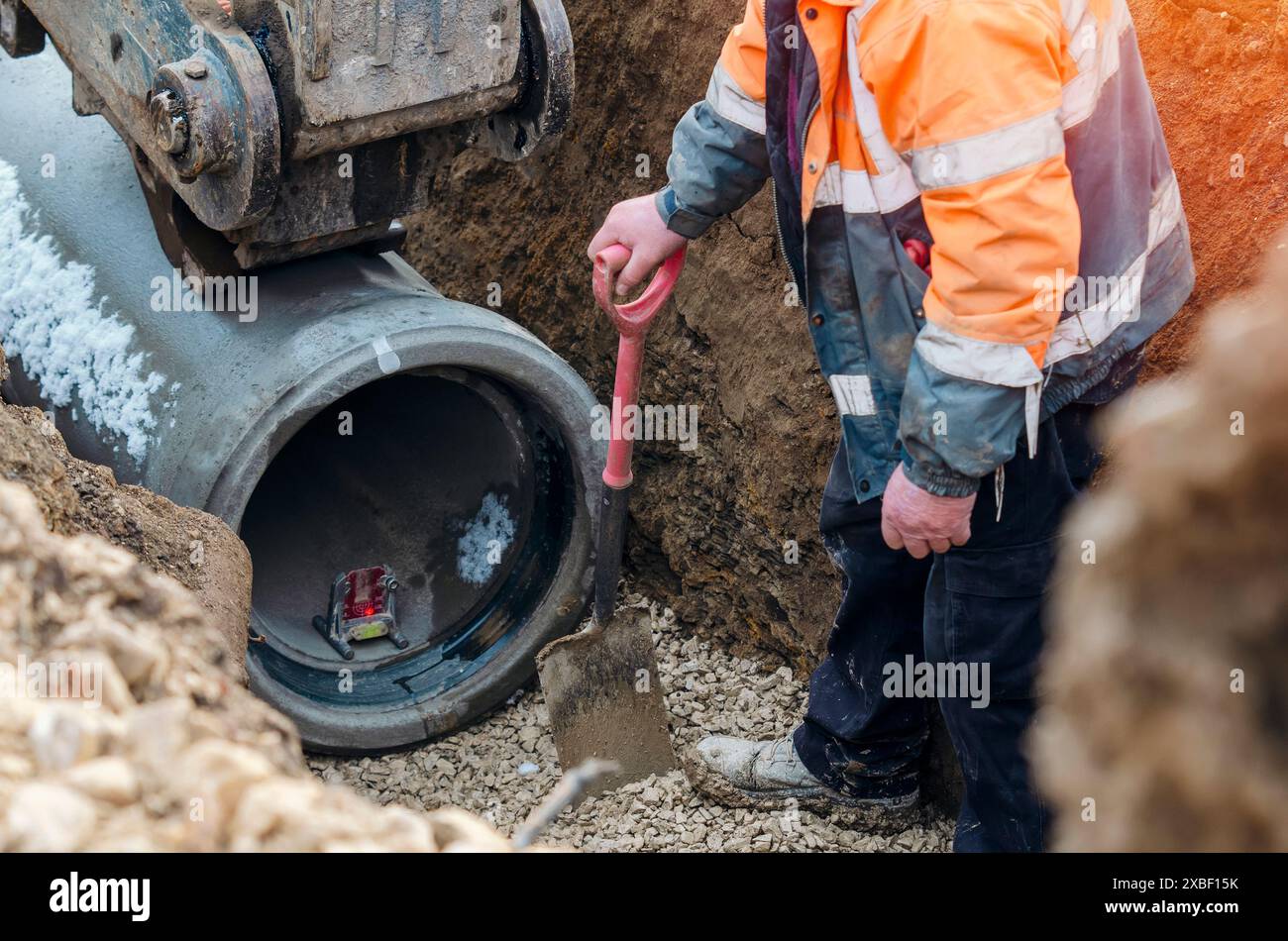 Lavoratori a terra che posano nuovi tubi in calcestruzzo durante i lavori di drenaggio profondo del nuovo progetto di edilizia abitativa Foto Stock