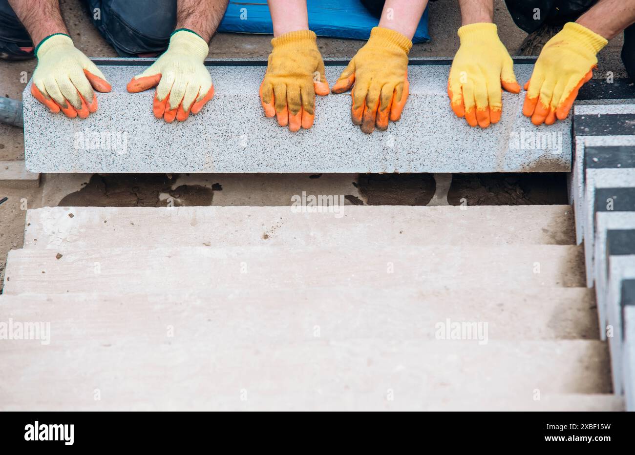 Passi concreti in costruzione come un team di costruttori installare blocchi di cemento pesanti Foto Stock