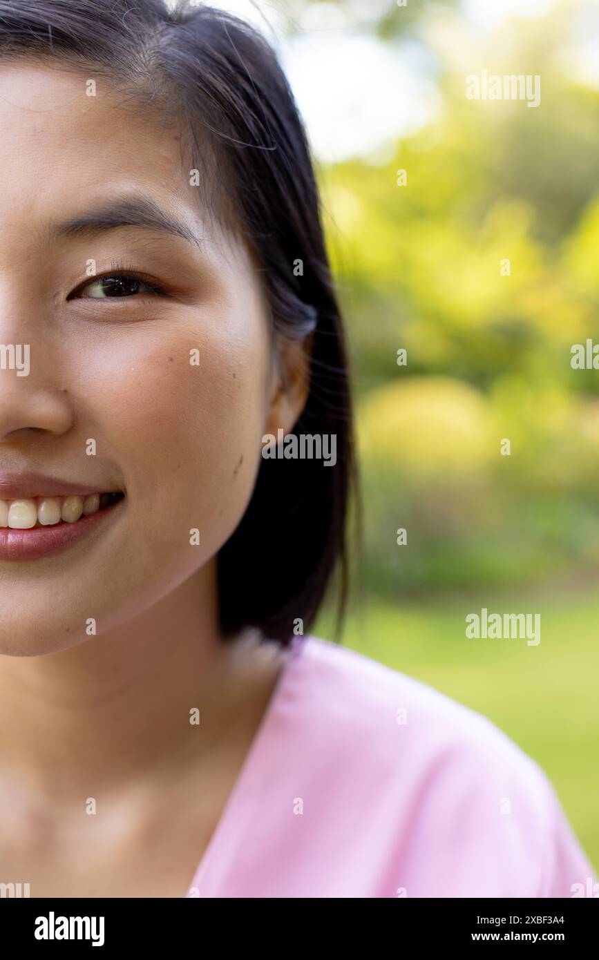Giovane donna asiatica sorridente calorosamente, fuori in giardino, a casa Foto Stock