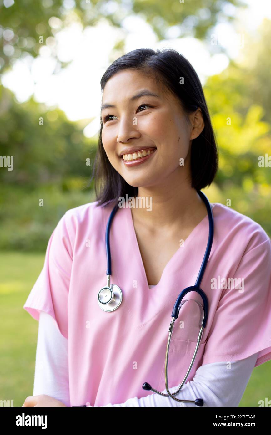 Infermiera asiatica con stetoscopio sorridente calorosamente a casa Foto Stock