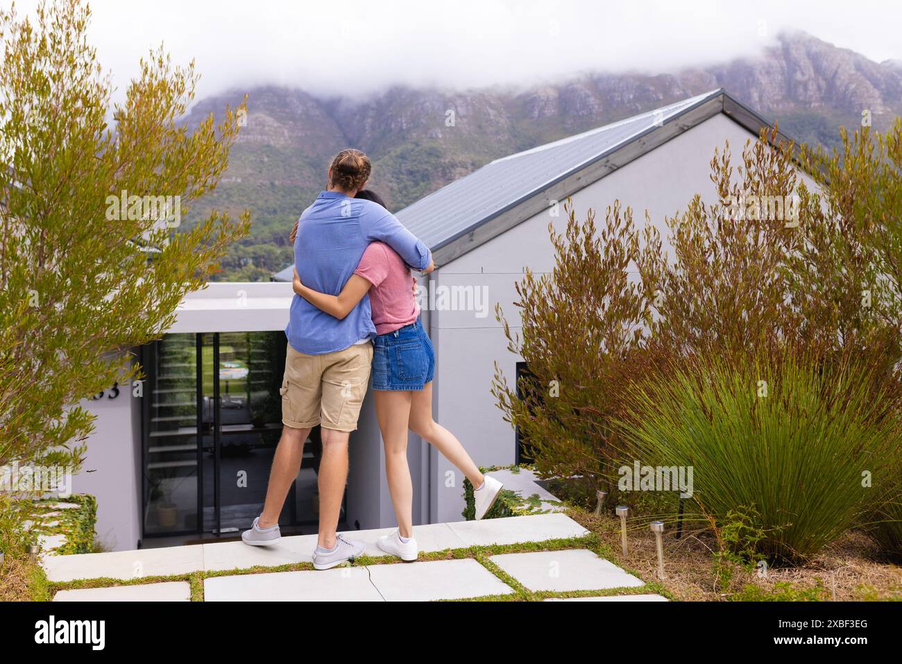 Diverse coppie si abbracciano mentre guardano la loro casa moderna Foto Stock