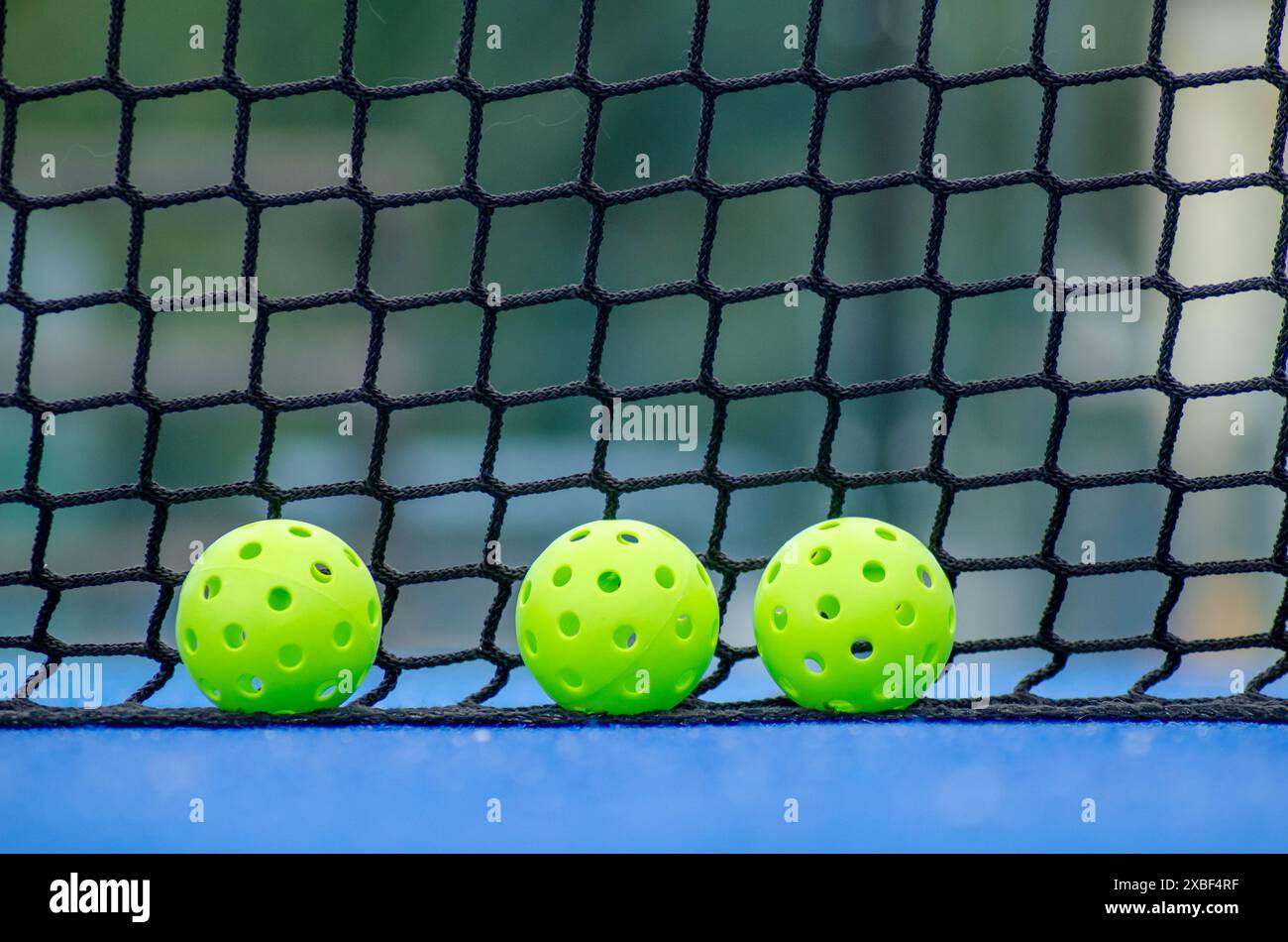 tre palline da picchetto verdi accanto alla rete di un campo da pallacanestro, nuovo sport a racchetta Foto Stock