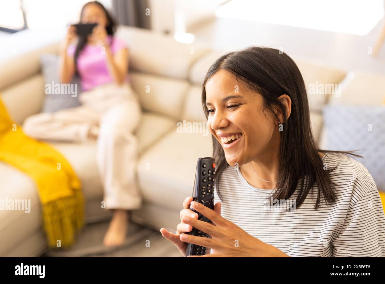 Due giovani amici birazziali che si divertono insieme, uno che tiene lontano e sorride, a casa Foto Stock