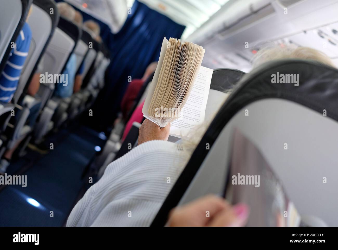 persona che legge un libro sull'aereo Foto Stock