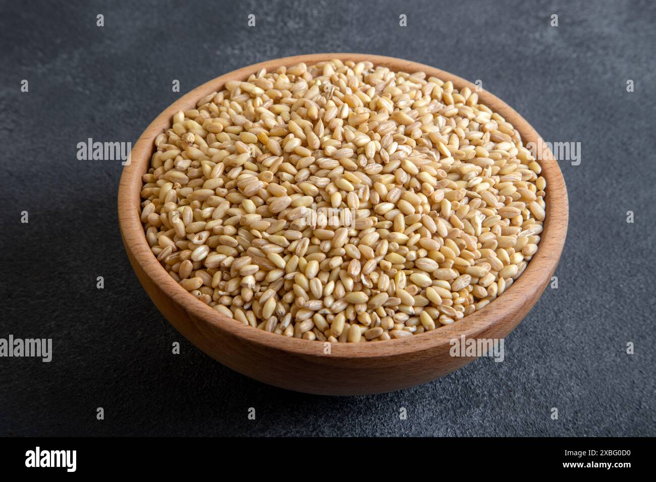Recipiente di legno in grani di grano su sfondo nero Foto Stock