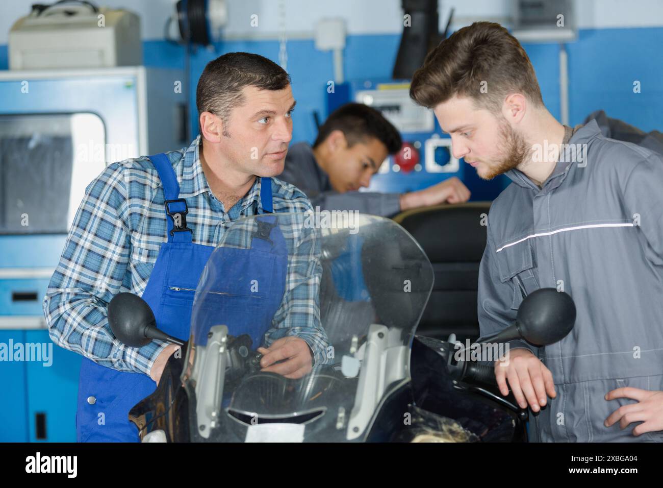 giovane apprendista che impara a riparare una moto Foto Stock