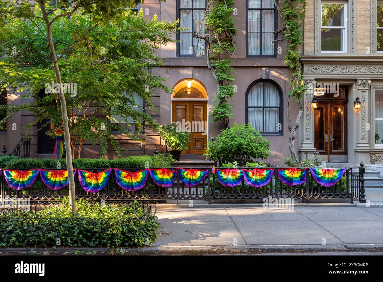 Case a schiera nel quartiere storico di Chelsea in estate con decorazioni con bandiera arcobaleno per celebrare il mese dell'orgoglio LGBTQ+. Manhattan, New York Foto Stock