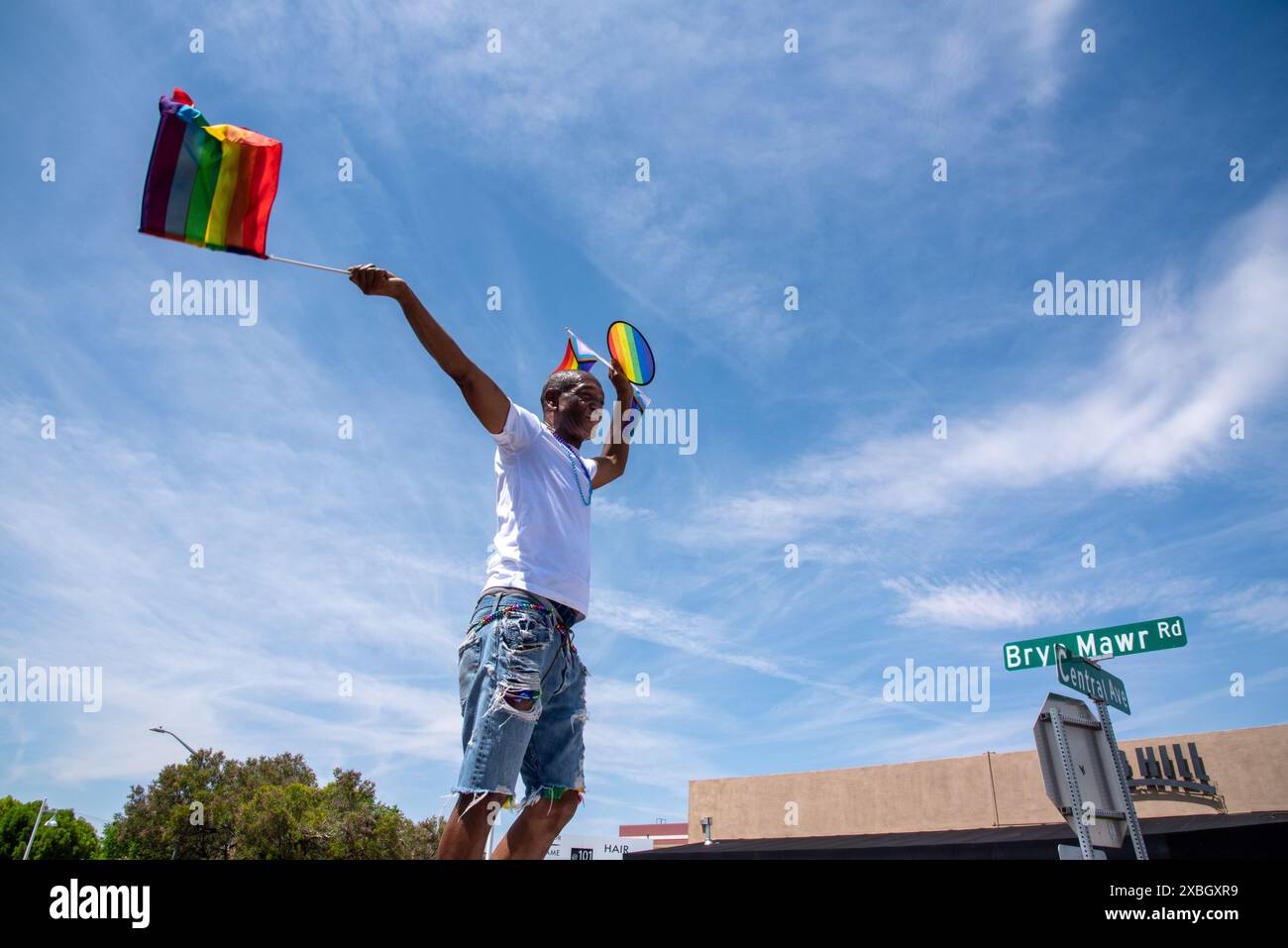 Uno spettatore alla Pride Parade 2024 balla con bandiera color arcobaleno e tchotchkes su Central Avenue, Route 66, Albuquerque, New Mexico, Stati Uniti. Foto Stock