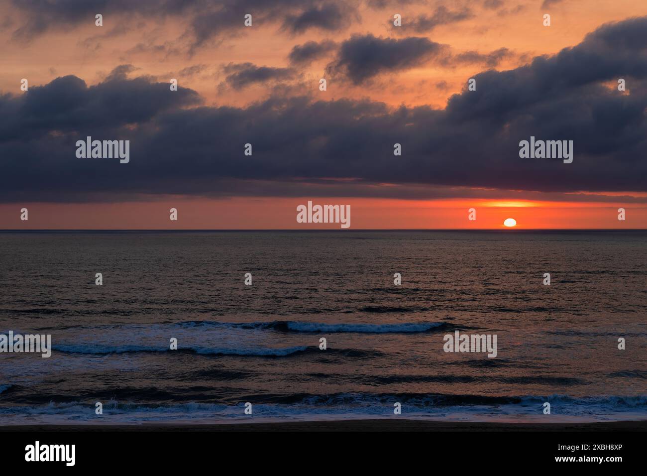 Il sole sorge nei cieli nuvolosi sull'Oceano Atlantico a Nags Head, a Outer Banks, North Carolina, Stati Uniti Foto Stock