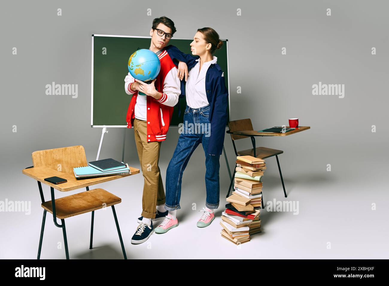 Due studenti universitari che tengono un globo davanti a un green board. Foto Stock