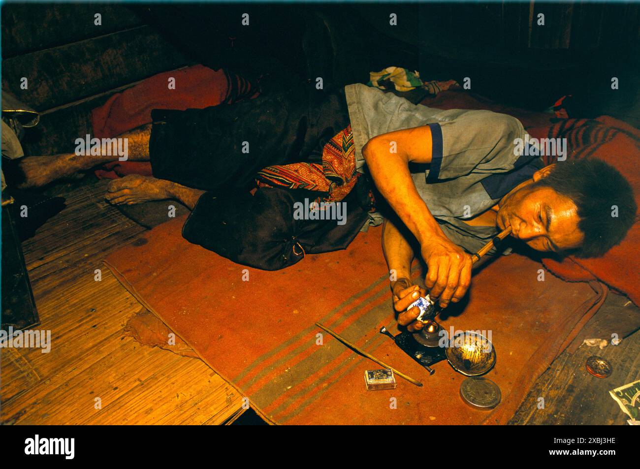 Uso di droghe, fumo di oppio. Contadini contadini di collina all'interno di questa casa. Inseguendo il drago, e' un drogato da oppio. Villaggio di Hmong, provincia di Chiang Rai, Thailandia del Nord, 1995 circa. HOMER SYKES anni '1990 Foto Stock