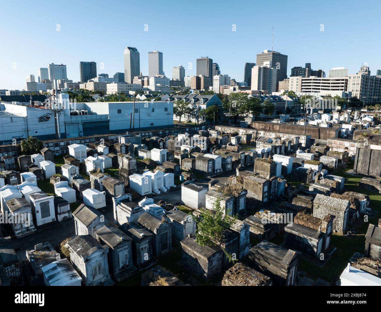 Vista aerea di uno storico cimitero di New Orleans con innumerevoli tombe e camere sepolcrali, giustapposte allo skyline moderno della città sullo sfondo. Foto Stock