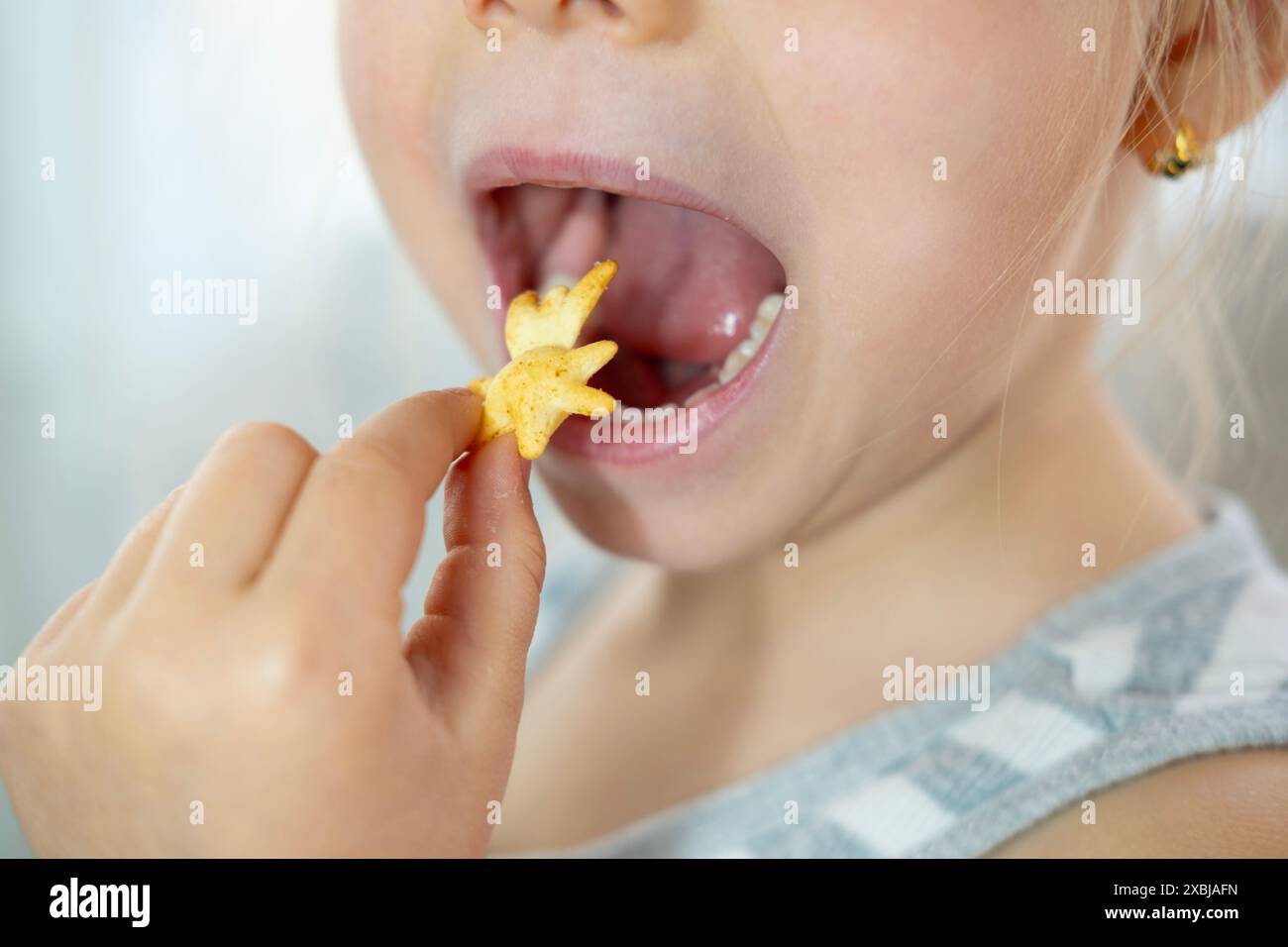 Carino allegro bambino piccolo, bionda ragazza di 5 anni gode di cracker, felice infanzia, dolce vita, cibo malsano, alimentazione bambino Foto Stock