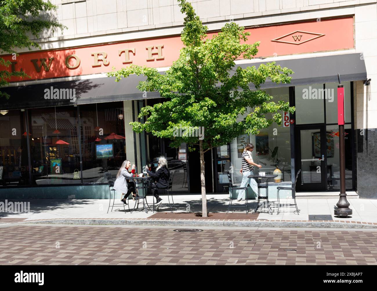 Asheville, North Carolina, USA-4 maggio 2023: Due donne al tavolo del marciapiede di fronte al vecchio edificio Woolworth su Haywood Ave. Foto Stock