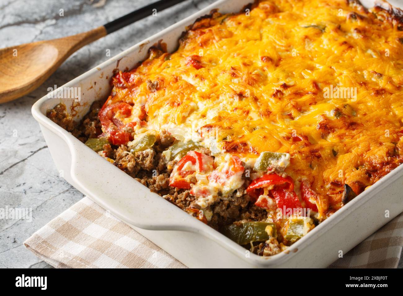 Strati di manzo macinato, formaggio, verdure fresche e peperoni Jalapeno cotti al forno sul piatto da forno sul tavolo. Orizzontale Foto Stock