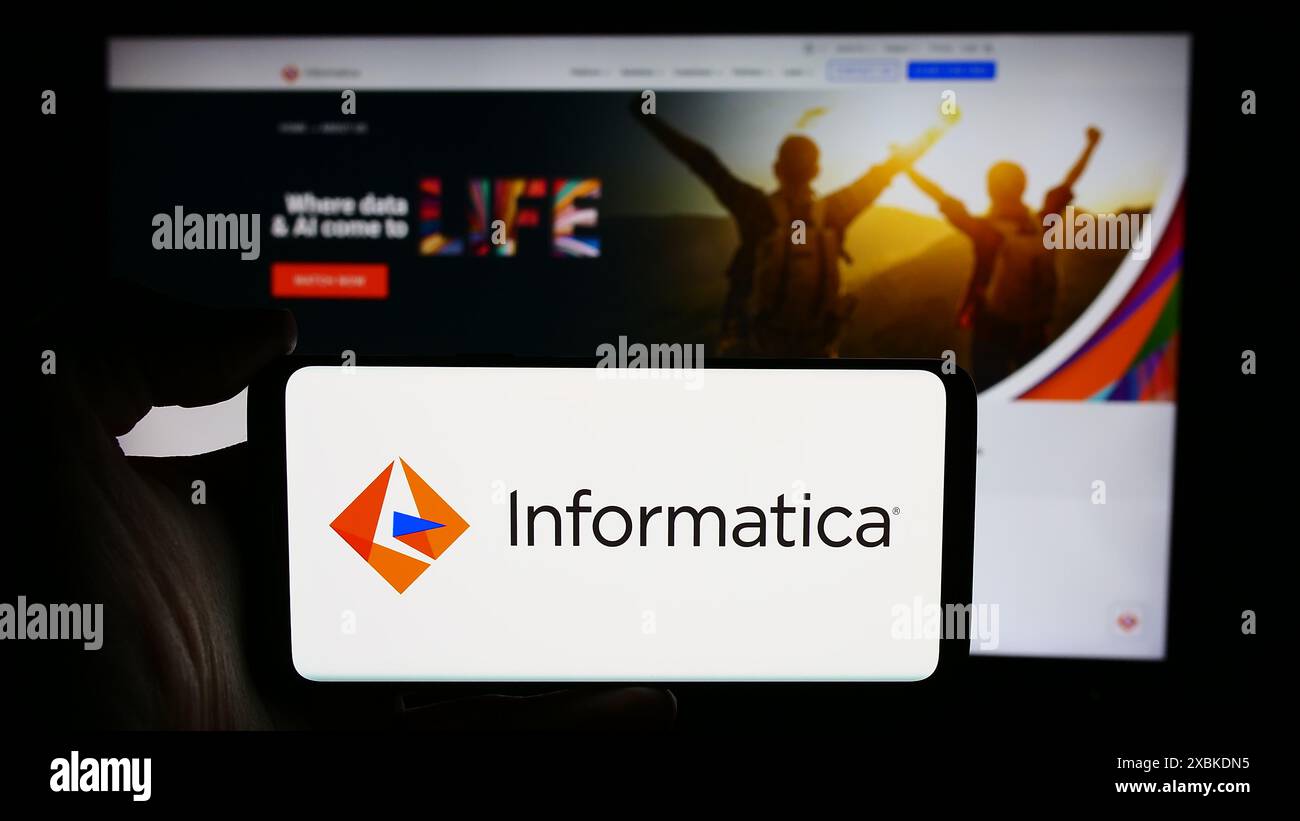 Persona che detiene lo smartphone con il logo della società di sviluppo software statunitense Informatica Inc. Davanti al sito Web. Mettere a fuoco il display del telefono. Foto Stock