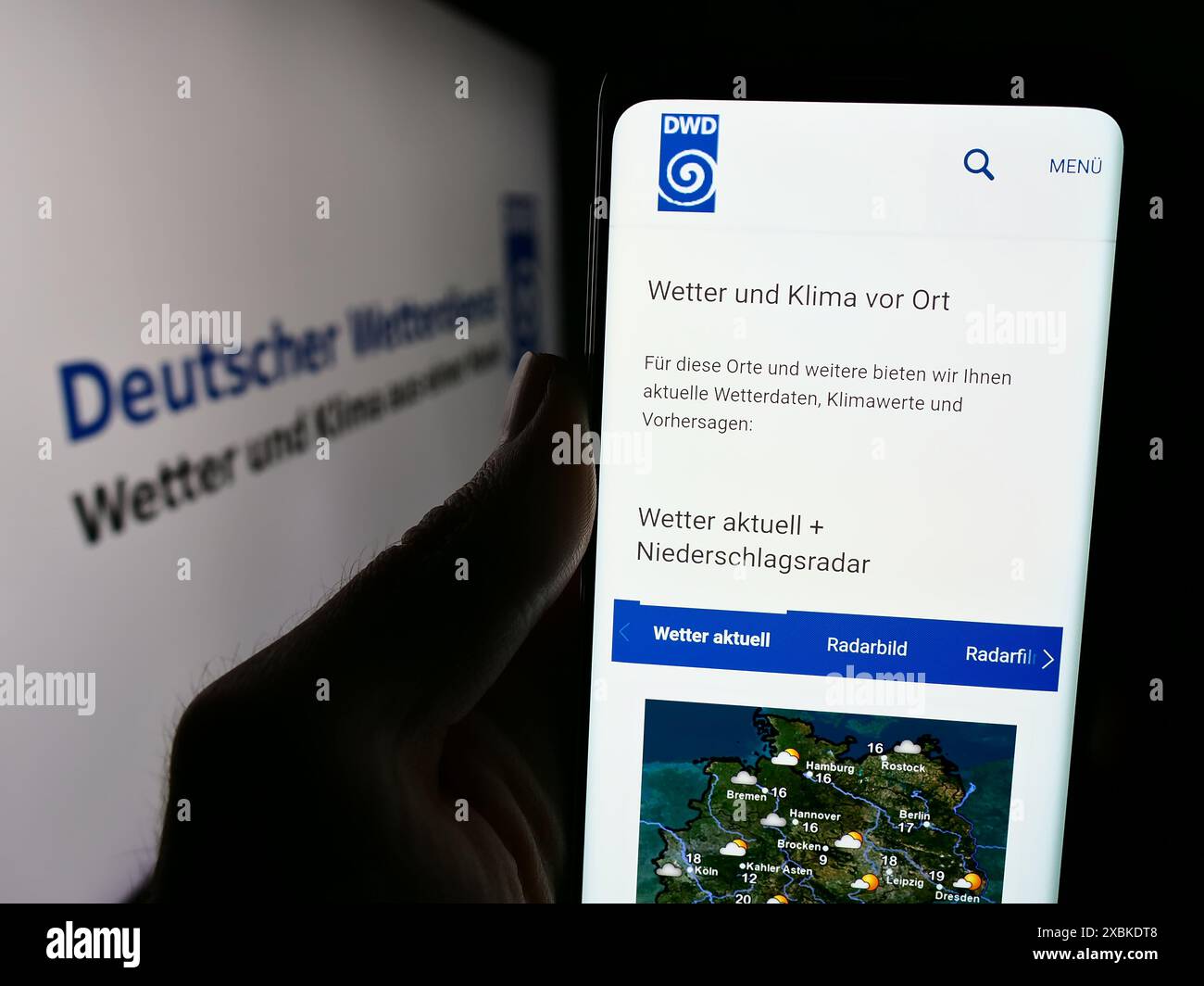Persona che detiene un cellulare con pagina web del servizio meteorologico tedesco Deutscher Wetterdienst (DWD) con logo. Messa a fuoco al centro del display del telefono. Foto Stock