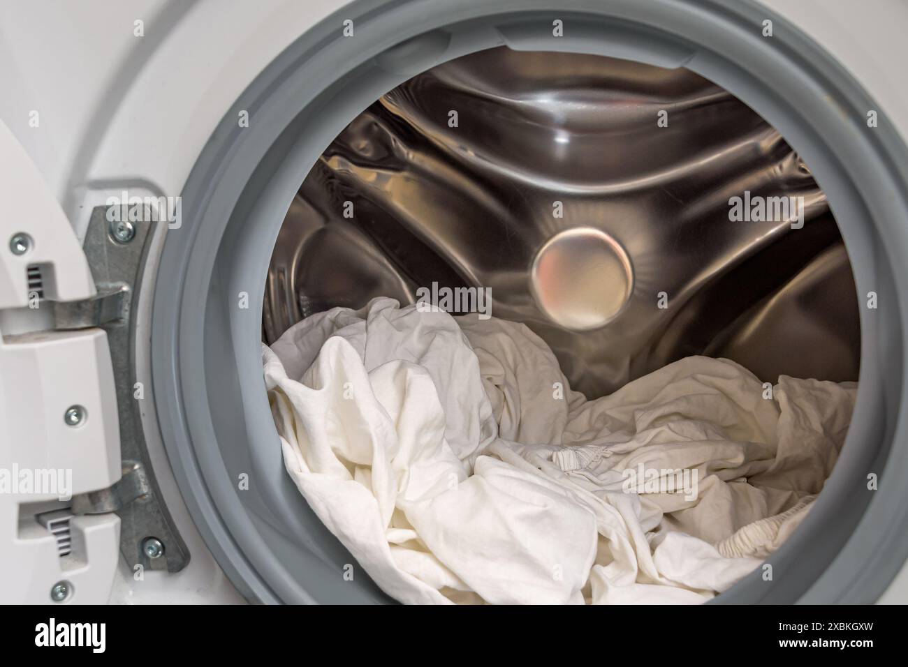 Vestiti bianchi in una lavatrice aperta. Concetto di lavanderia Foto Stock