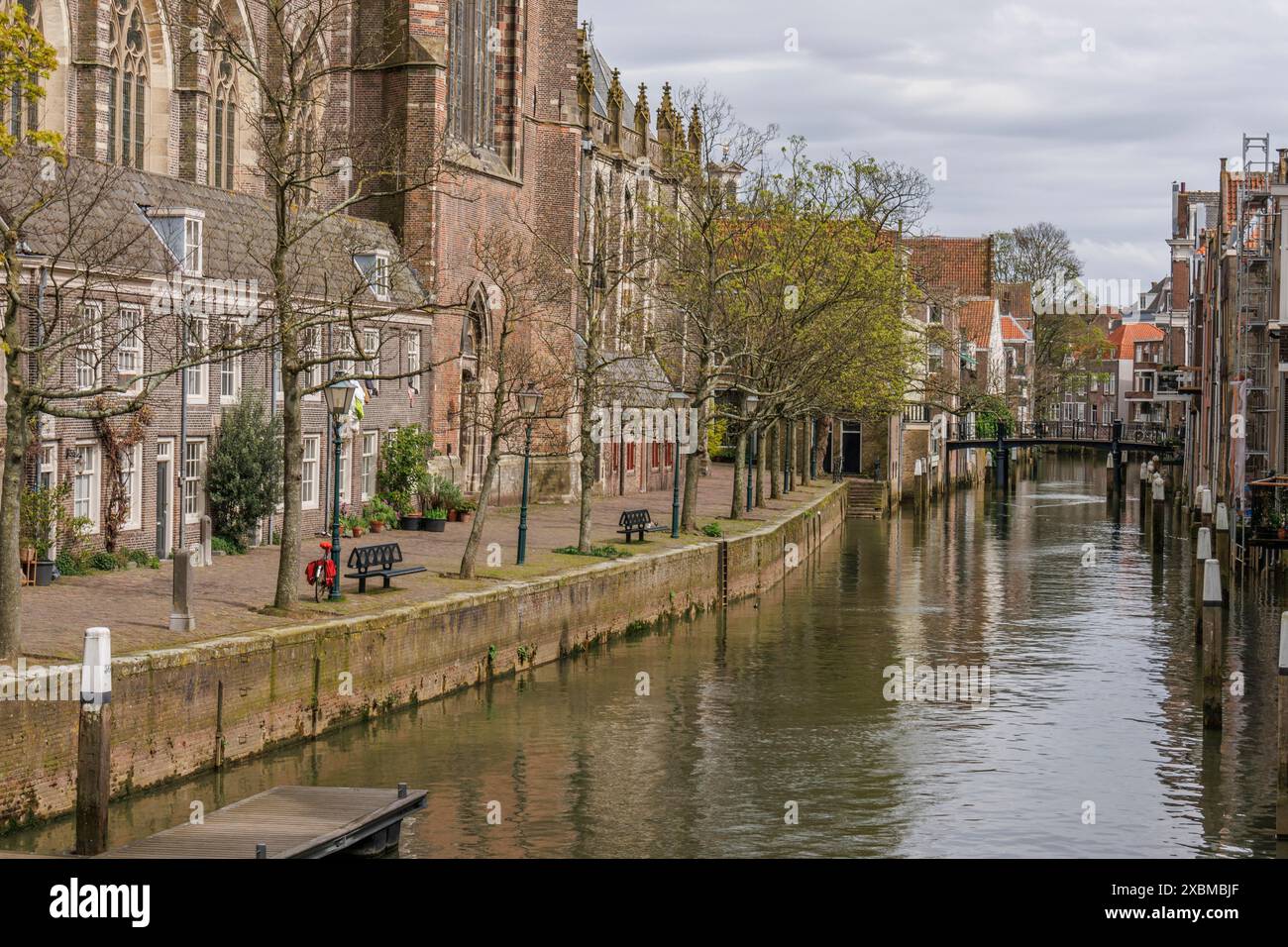 Pittoresca scena lungo un canale con edifici storici, alberi e passerella, vista della chiesa, Dordrecht, olanda, paesi bassi Foto Stock