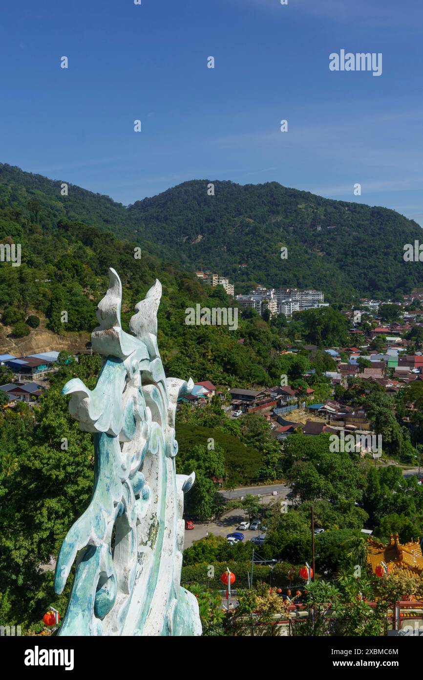 Vista di un villaggio sulle colline con una statua decorativa di drago in primo piano sotto un cielo azzurro soleggiato, Pattaya, Thailandia Foto Stock