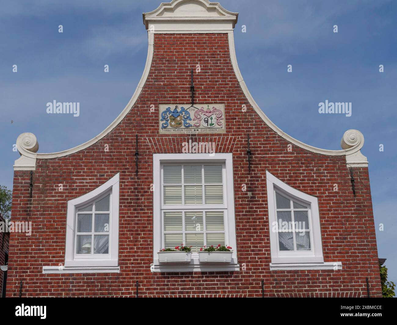 Una facciata di un edificio storico con pareti in mattoni rossi e cornici bianche per finestre, Greetsiel, Frisia Orientale, bassa Sassonia, Germania Foto Stock