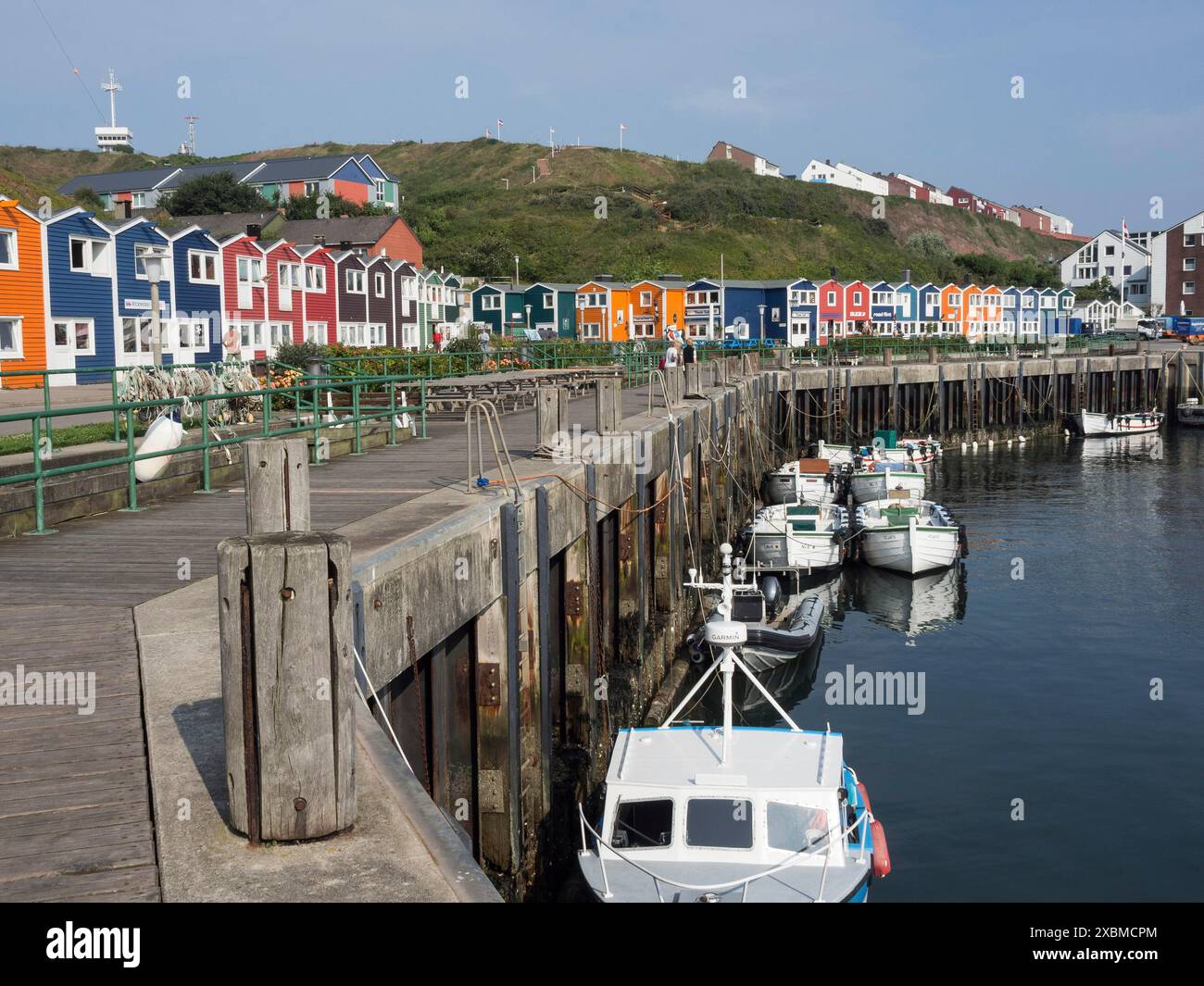 Barche ormeggiate su un molo di legno di fronte a una fila di case colorate, Helgoland, Mare del Nord, Germania Foto Stock