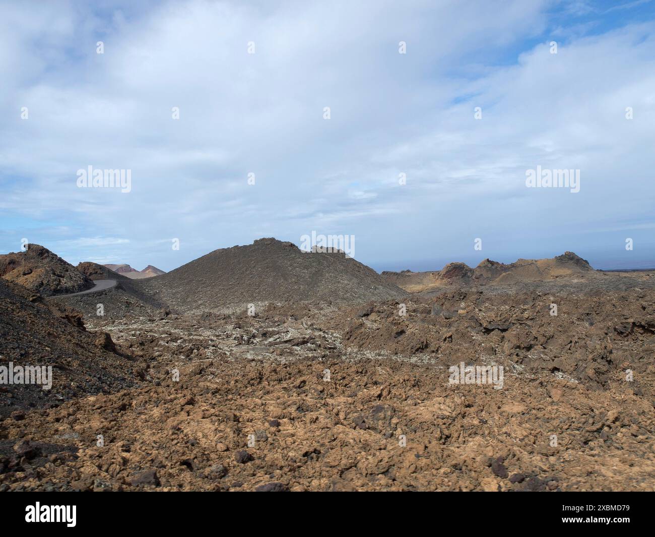 Ampio paesaggio vulcanico con colline rocciose sotto un cielo grigio-blu, arrecife, Lanzarote, Isole Canarie, Spagna Foto Stock