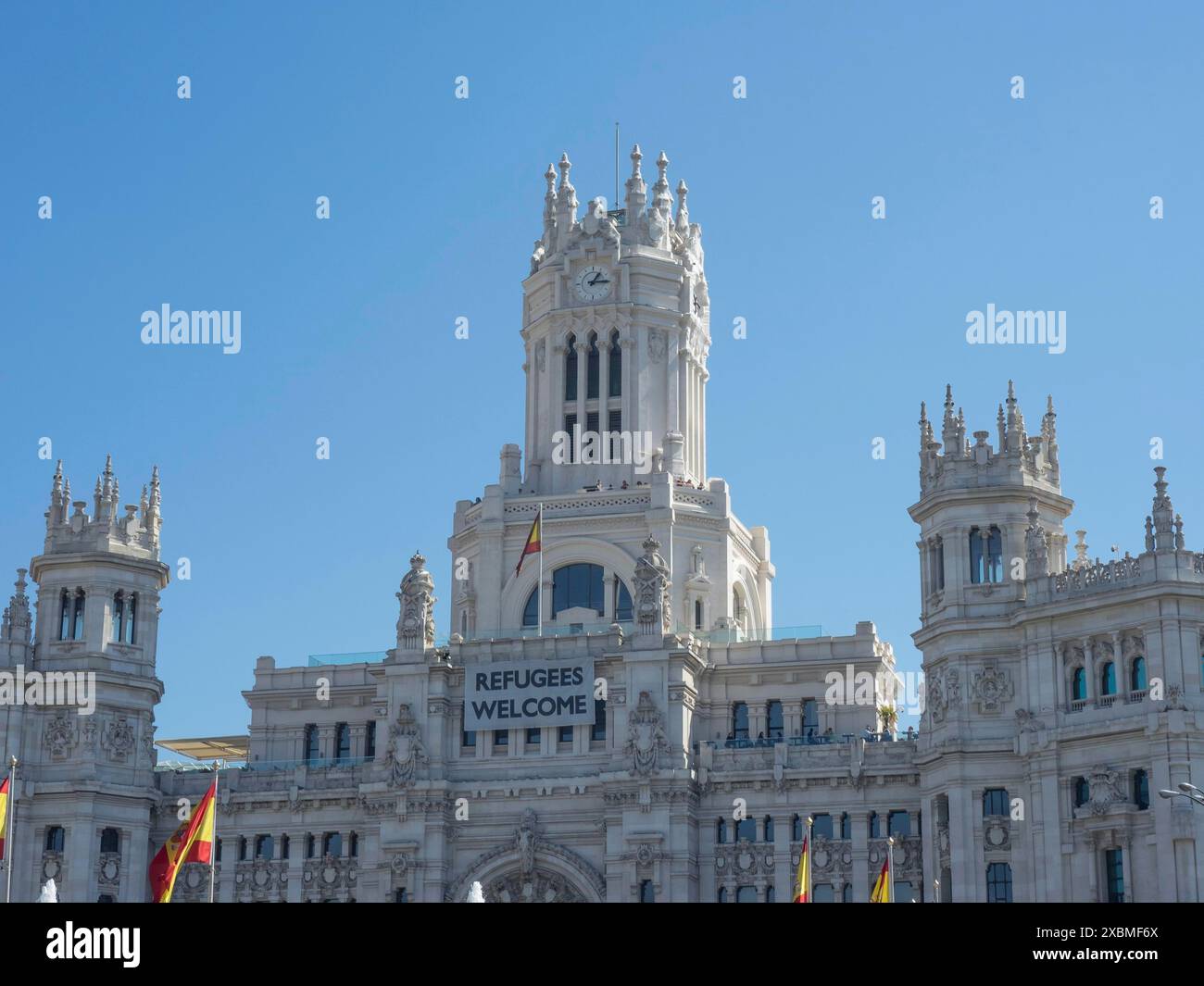 Un grande edificio con dettagli gotici e uno striscione. Bandiere spagnole che sventolano di fronte a un cielo blu, Madrid, Spagna Foto Stock