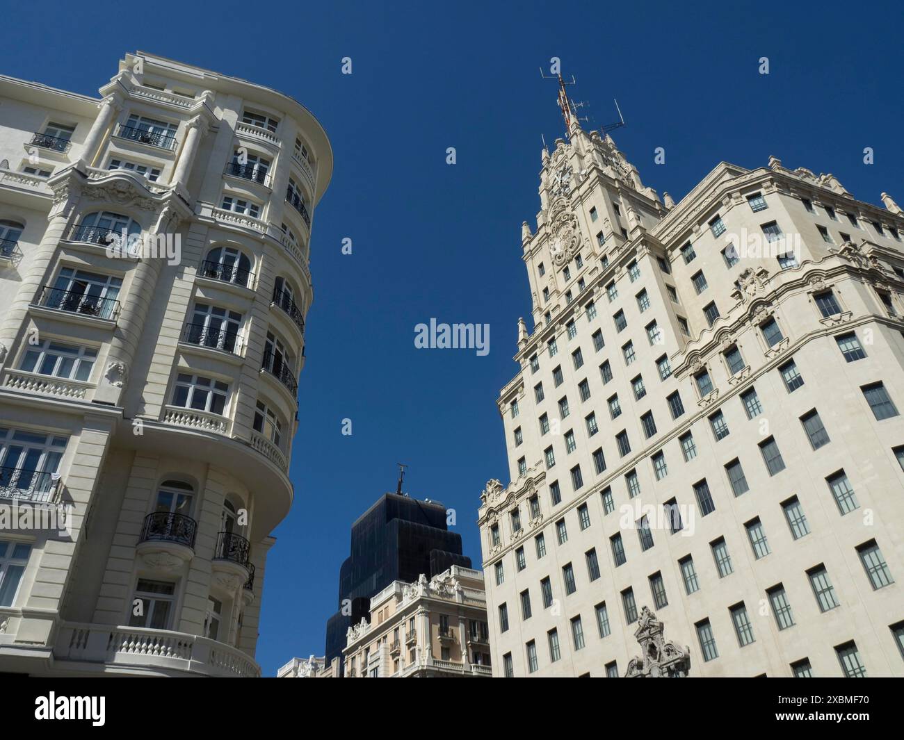 Due grandi edifici con ricche facciate e dettagli strutturali. Il cielo è blu profondo e nuvoloso, Madrid, Spagna Foto Stock