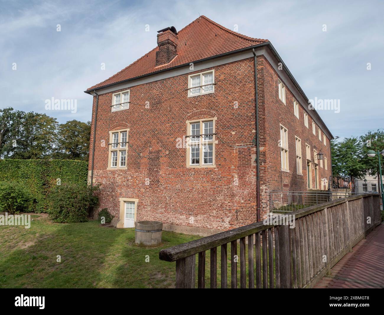 Edificio in mattoni con tetto a timpano e camino, circondato da un prato verde e una recinzione in legno, ramsdorf, muensterland, Germania Foto Stock