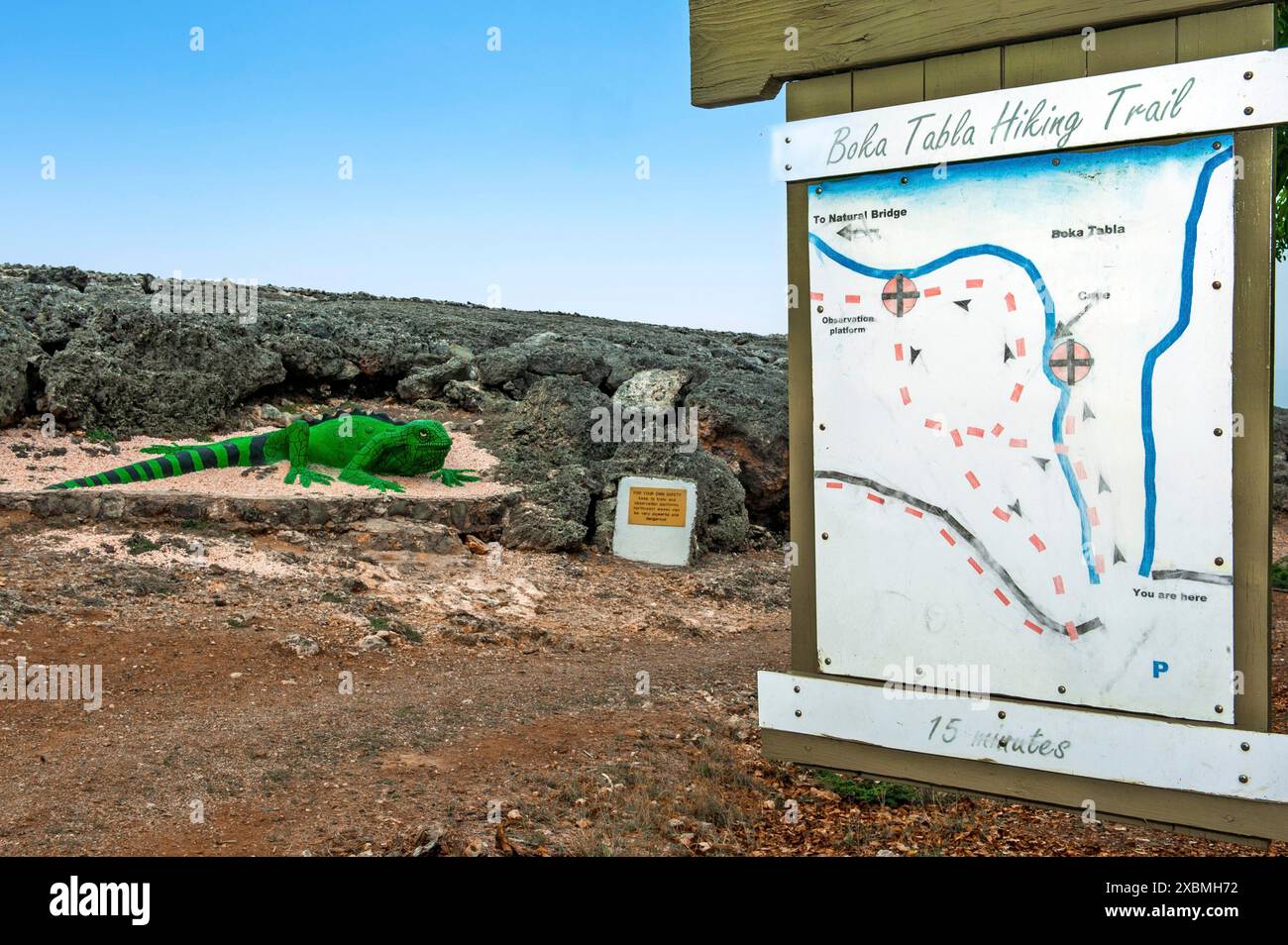 Cartello con la mappa panoramica del sito per escursionisti e turisti all'inizio del sentiero escursionistico Boka Tabla, ha lasciato iguano verde velenoso artificiale di grandi dimensioni Foto Stock