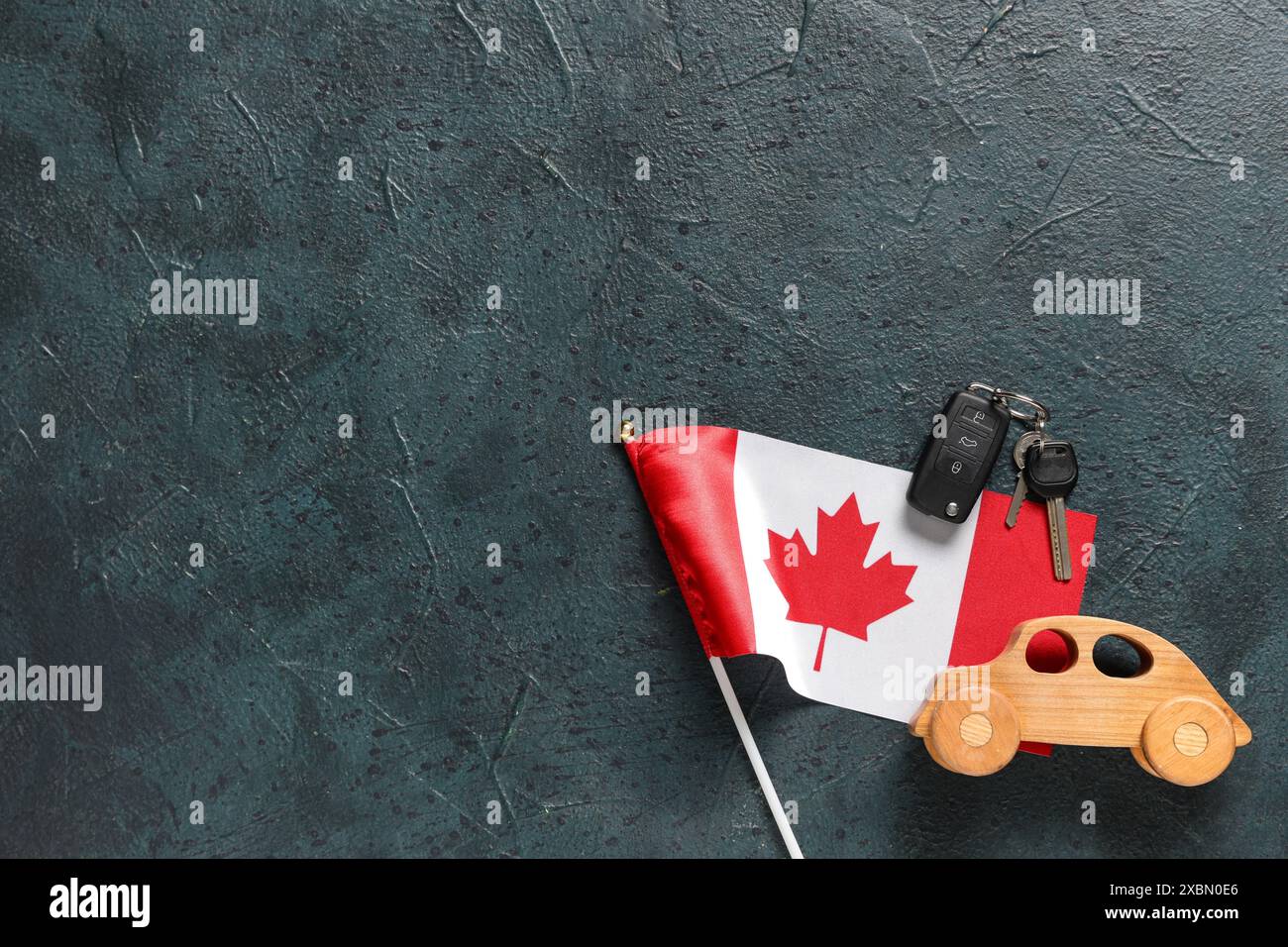 Auto in legno, chiavi e bandiera canadese su sfondo colorato Foto Stock