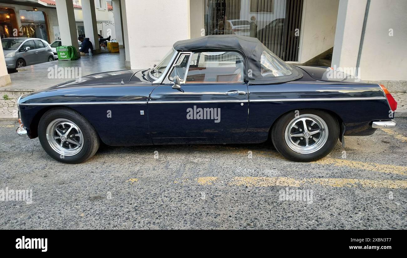 Roadster MG MGB 1970-S blu scuro parcheggiata sul marciapiede, lato sinistro, lato conducente, vista laterale Foto Stock