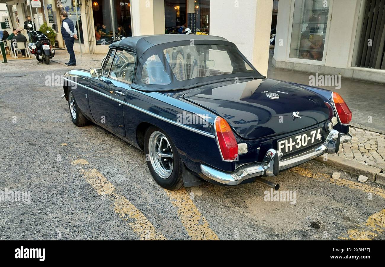 Roadster MG MGB 1970-S blu scuro parcheggiato sul marciapiede, vista dall'angolo posteriore sinistro Foto Stock