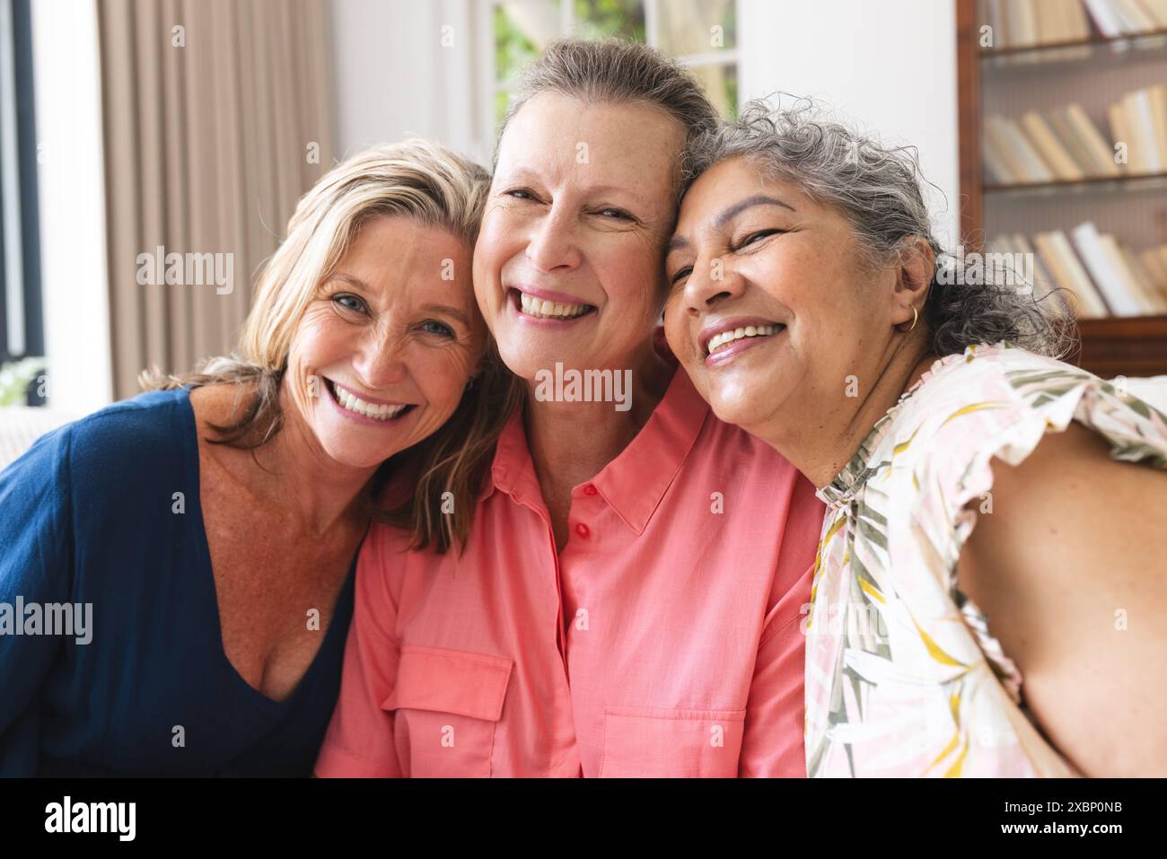 Gruppo eterogeneo di donne mature che sorridono nel soggiorno di casa al chiuso Foto Stock