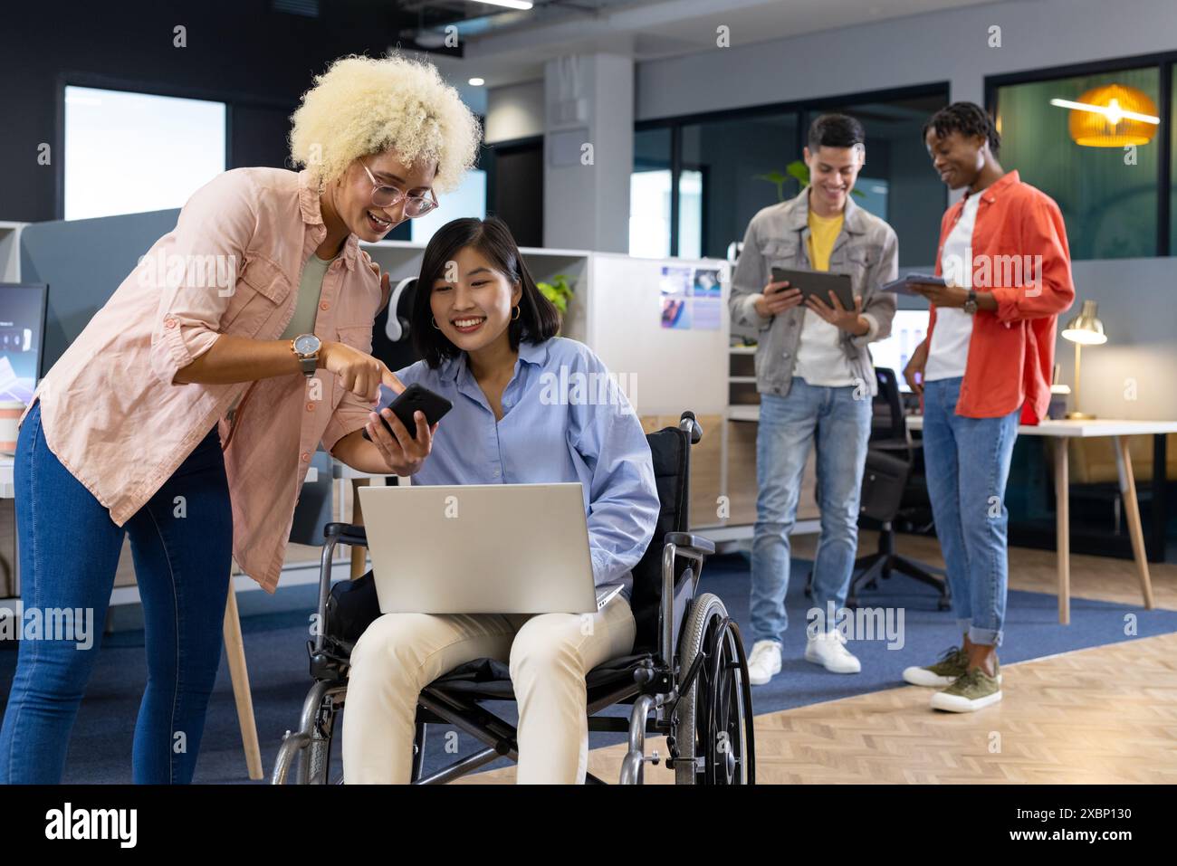Colleghi di diverse origini collaborano utilizzando la tecnologia in un ambiente moderno di startup Foto Stock