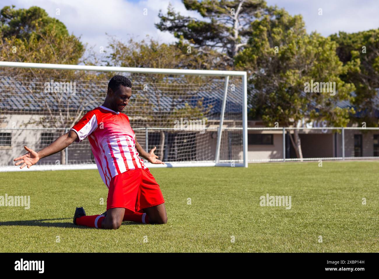 Giocatore di calcio afroamericano che festeggia sul campo di calcio, sembra forte e in forma, copia spazio Foto Stock