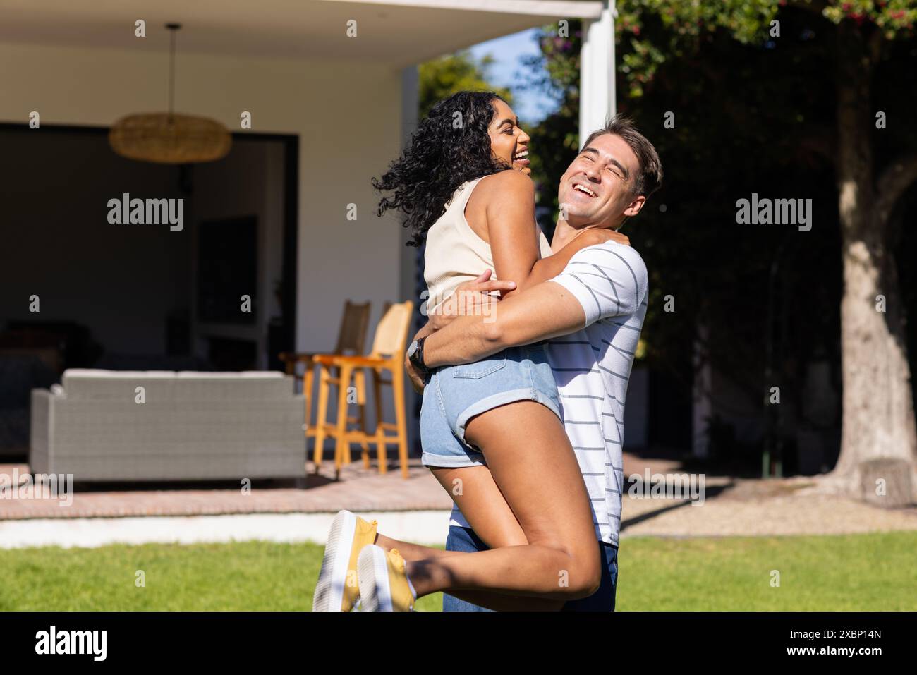 Giovane uomo caucasico che solleva e sorride al suo partner asiatico in un abbraccio giocoso, copia spazio Foto Stock