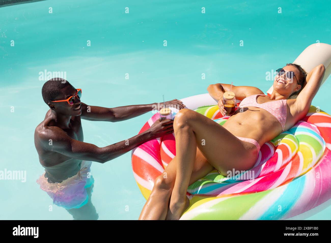 Coppie diverse che si godono una giornata di sole in piscina Foto Stock