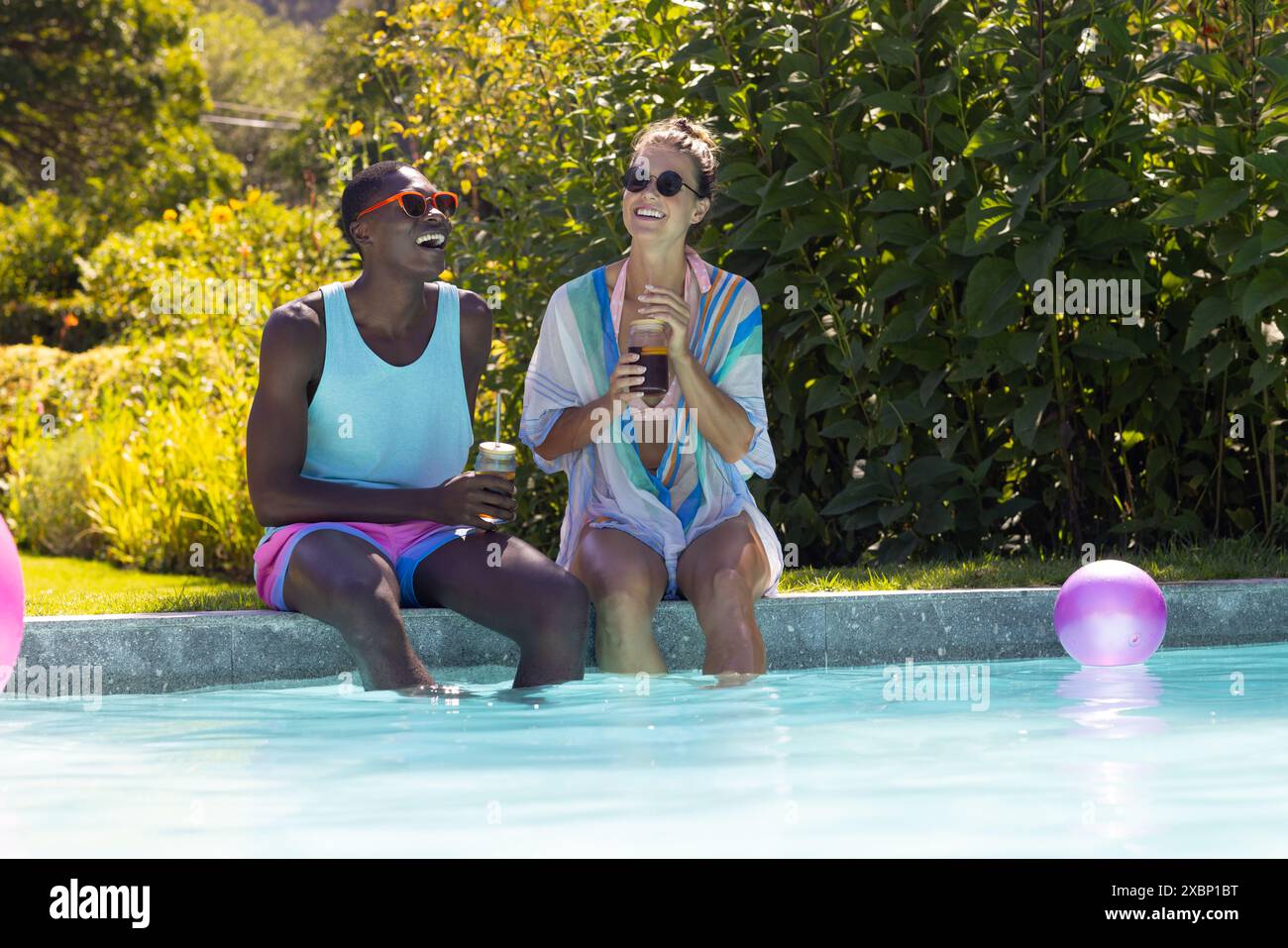 Coppie diverse che si rilassano a bordo piscina, si godono bevande e il sole estivo, si sentono felici Foto Stock