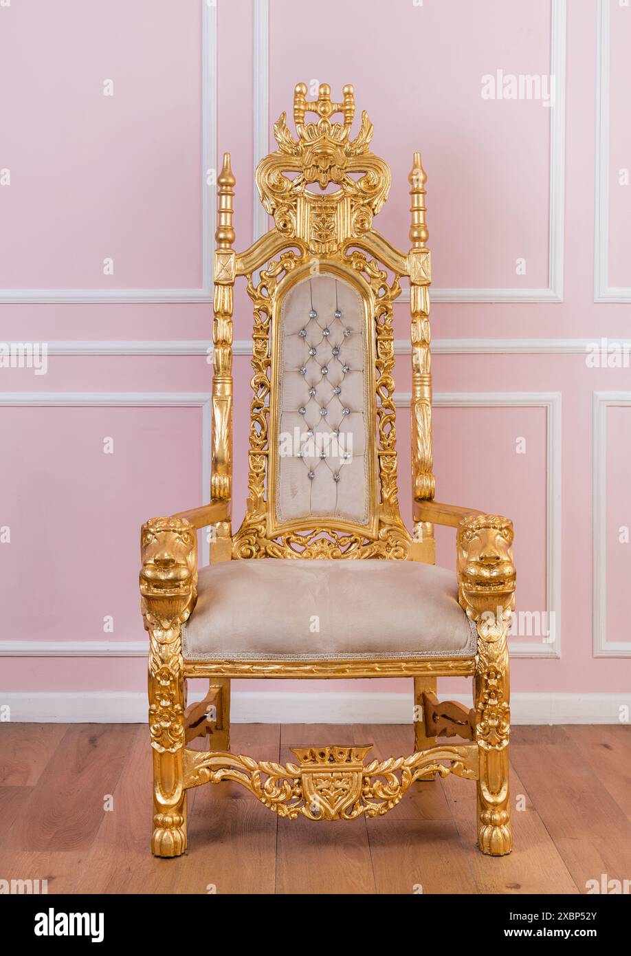 Poltrona ornamentale vintage dorata collocata su una parete rosa in una stanza luminosa durante il giorno Foto Stock