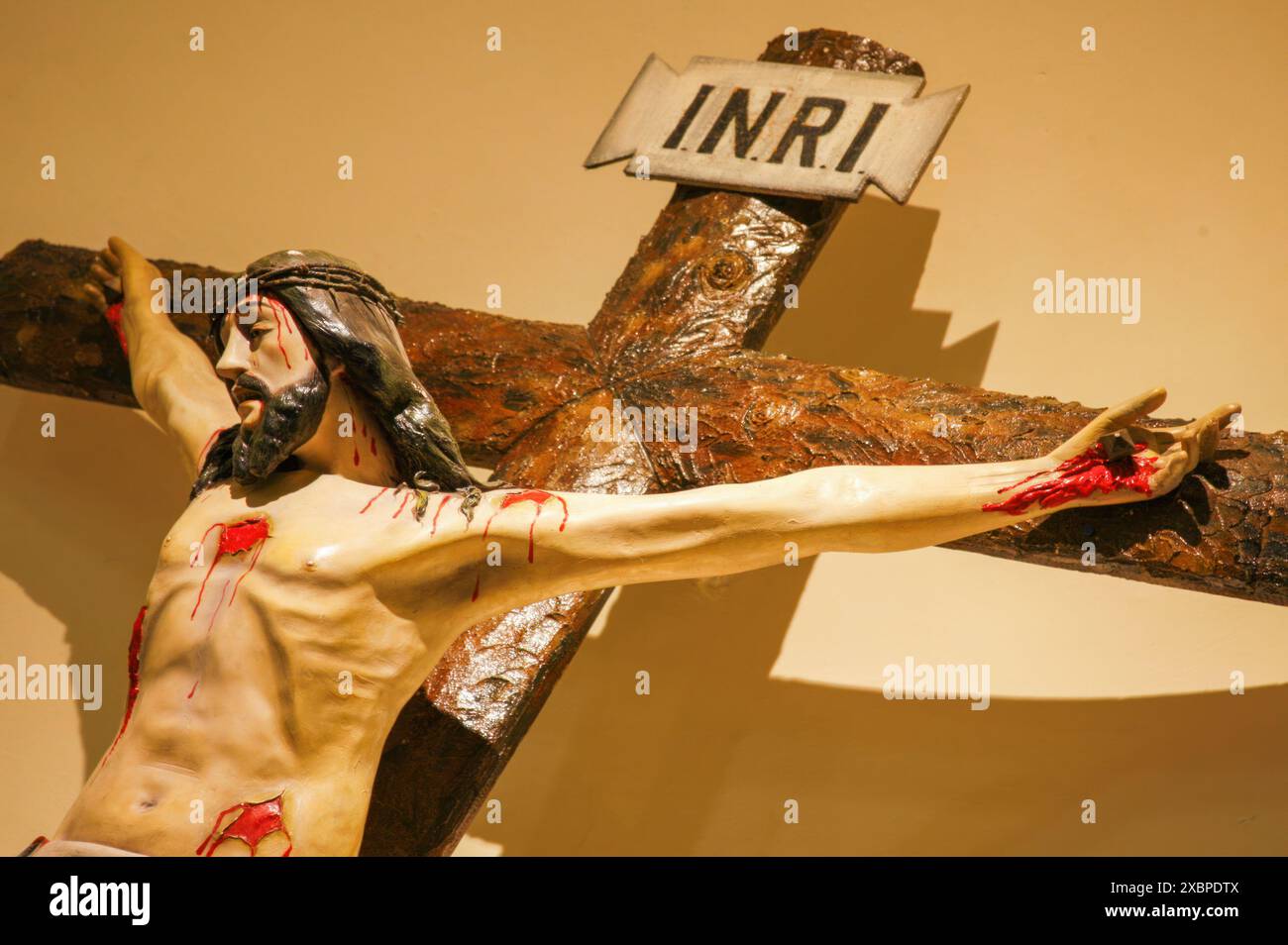 Statua di gesù cristo crocifisso su una croce di legno, con sangue che gocciola dalle sue ferite Foto Stock