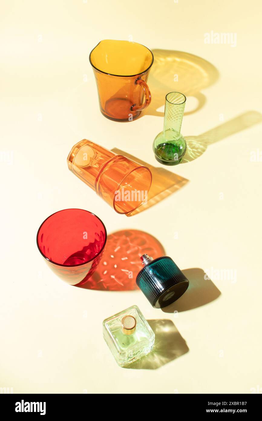 Disposizione creativa di oggetti in vetro colorati su luce diretta con ombre. Foto Stock