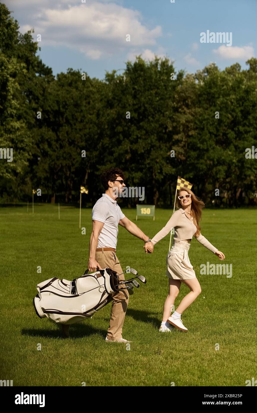 Una giovane coppia elegante, vestita elegantemente, cammina mano nella mano attraverso un lussureggiante campo da golf in una dimostrazione di raffinatezza classica. Foto Stock
